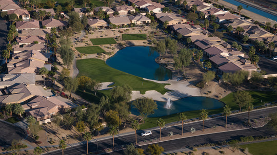 Aerial view of a suburban neighborhood with houses, roads, and a large pond in sun city shadow hills ca