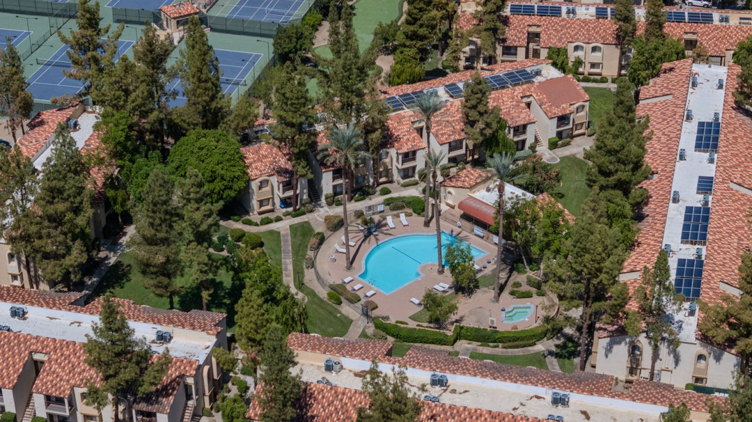 Aerial view of The Regent Palm Desert apartment buildings surrounding a landscaped pool courtyard. Photo by Mark Miller, September 10, 2026.