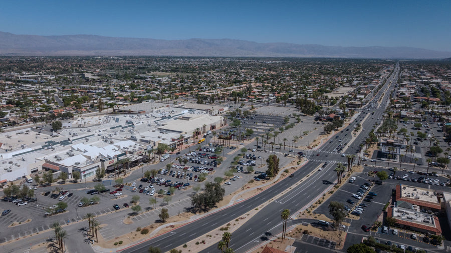 Aerial view of The Shops at Palm Desert, surrounding palm-lined streets, and distant desert mountains.